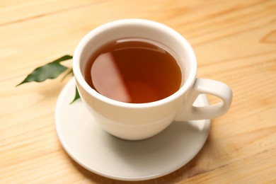 Photo of Tasty tea in cup on light wooden table, closeup