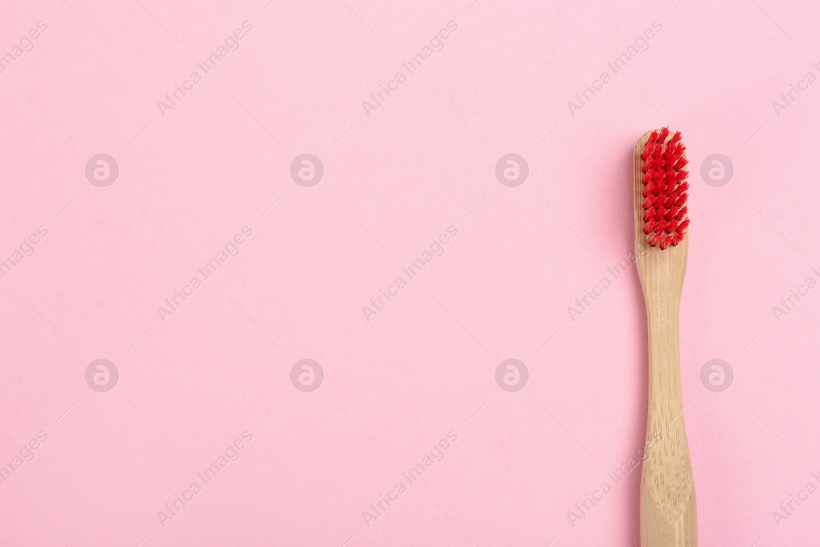 Photo of Toothbrush made of bamboo on pink background, top view. Space for text