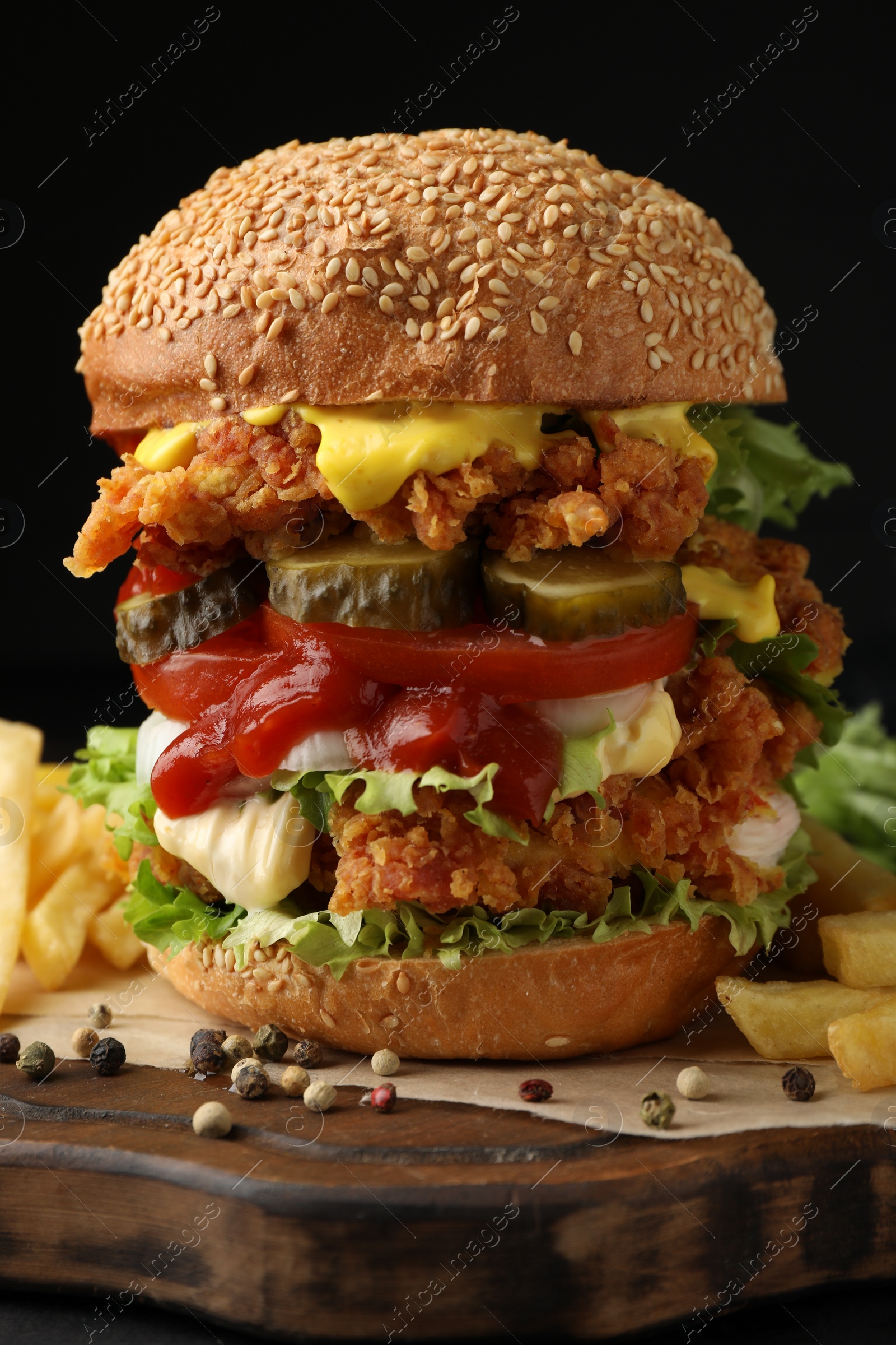 Photo of Delicious burger with crispy chicken patty and french fries on table, closeup