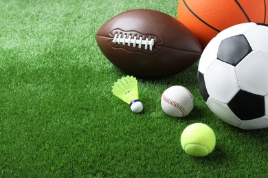 Photo of Set of different sport balls and shuttlecock on green grass. Space for text