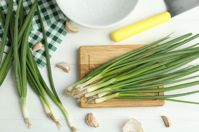 Flat lay composition with fresh green spring onions and garlic cloves on white wooden table