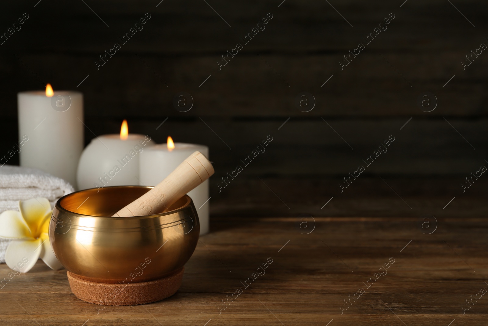 Photo of Composition with golden singing bowl on wooden table, space for text