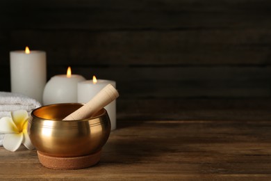 Photo of Composition with golden singing bowl on wooden table, space for text
