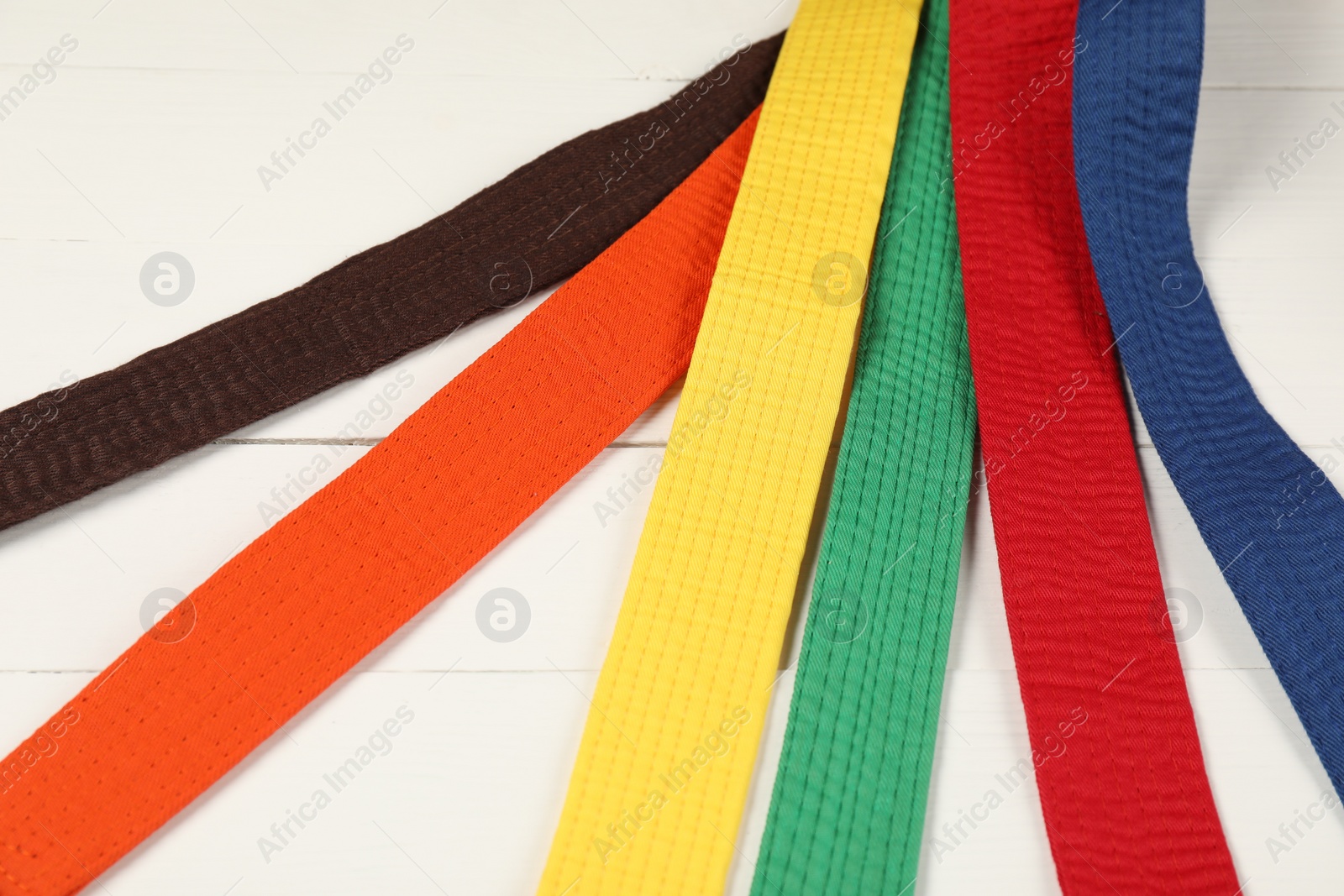 Photo of Colorful karate belts on wooden background, closeup