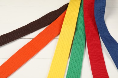 Colorful karate belts on wooden background, closeup