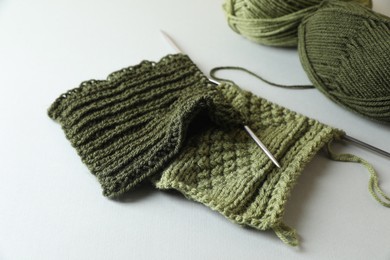 Green knitting, needles and soft yarns on light background