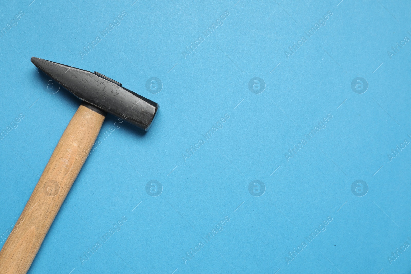 Photo of New hammer with wooden handle on light blue background, top view. Space for text