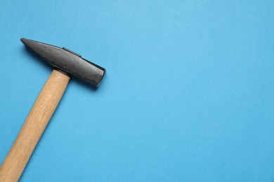 New hammer with wooden handle on light blue background, top view. Space for text