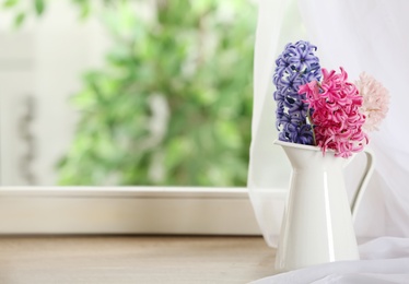 Photo of Beautiful fresh hyacinths on window sill indoors. Spring flowers