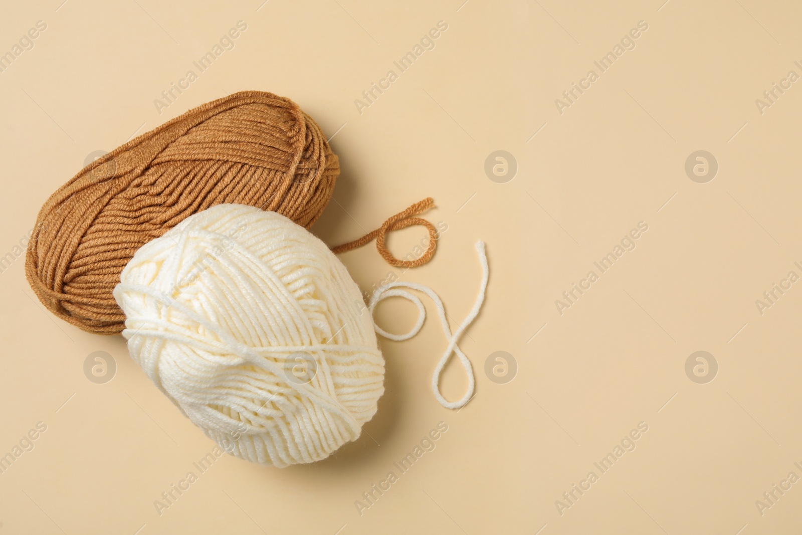 Photo of Soft woolen yarns on beige background, flat lay. Space for text