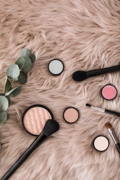 Photo of Flat lay composition with makeup brushes and cosmetic products on faux fur