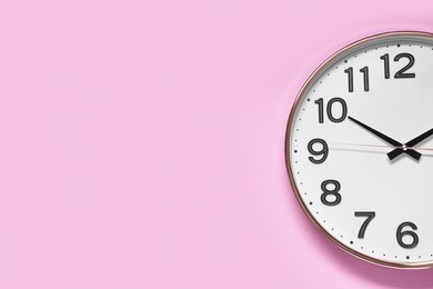 Photo of Stylish round clock on pale pink background, top view with space for text. Interior element