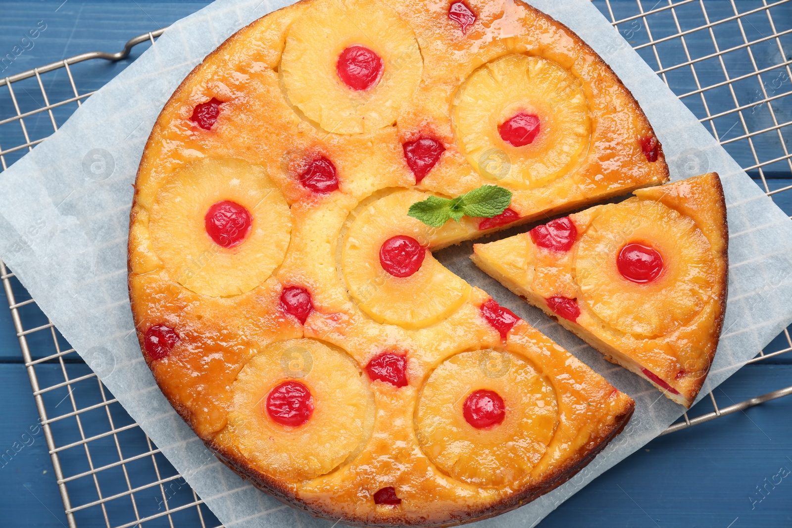 Photo of Delicious cut pineapple pie with cherry on blue wooden table, top view