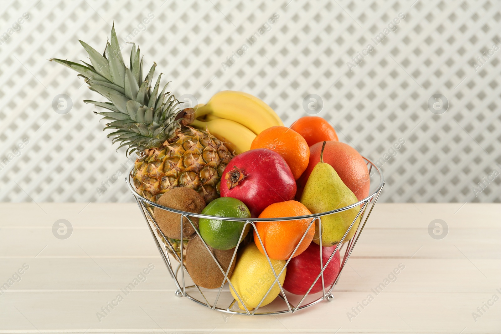 Photo of Fresh ripe fruits in metal bowl on white wooden table