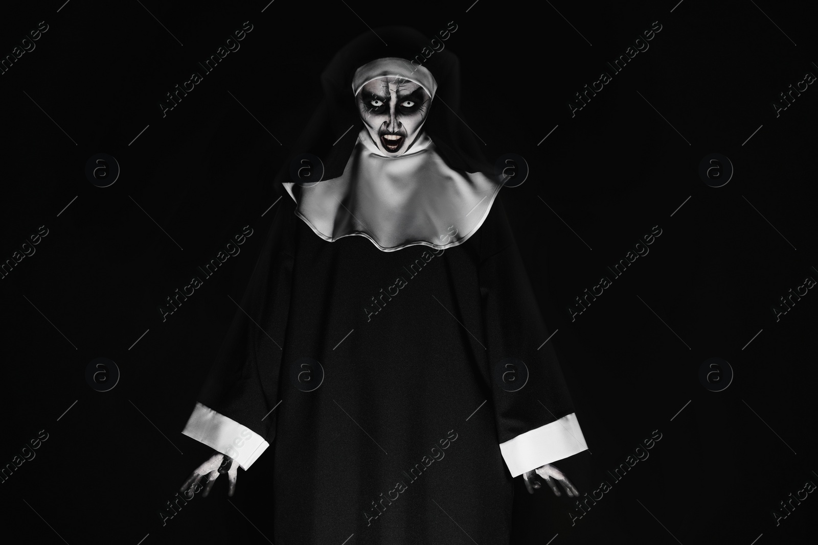 Photo of Portrait of scary devilish nun on black background. Halloween party look