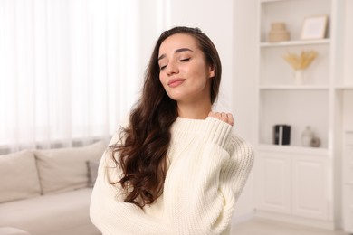 Photo of Beautiful young woman in stylish warm sweater at home