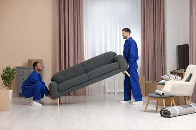 Photo of Male movers carrying sofa in new house