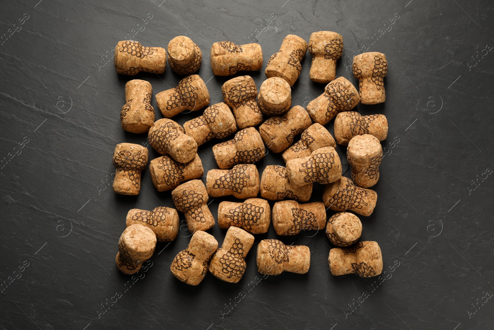 Photo of Sparkling wine corks with grape images on black table, flat lay