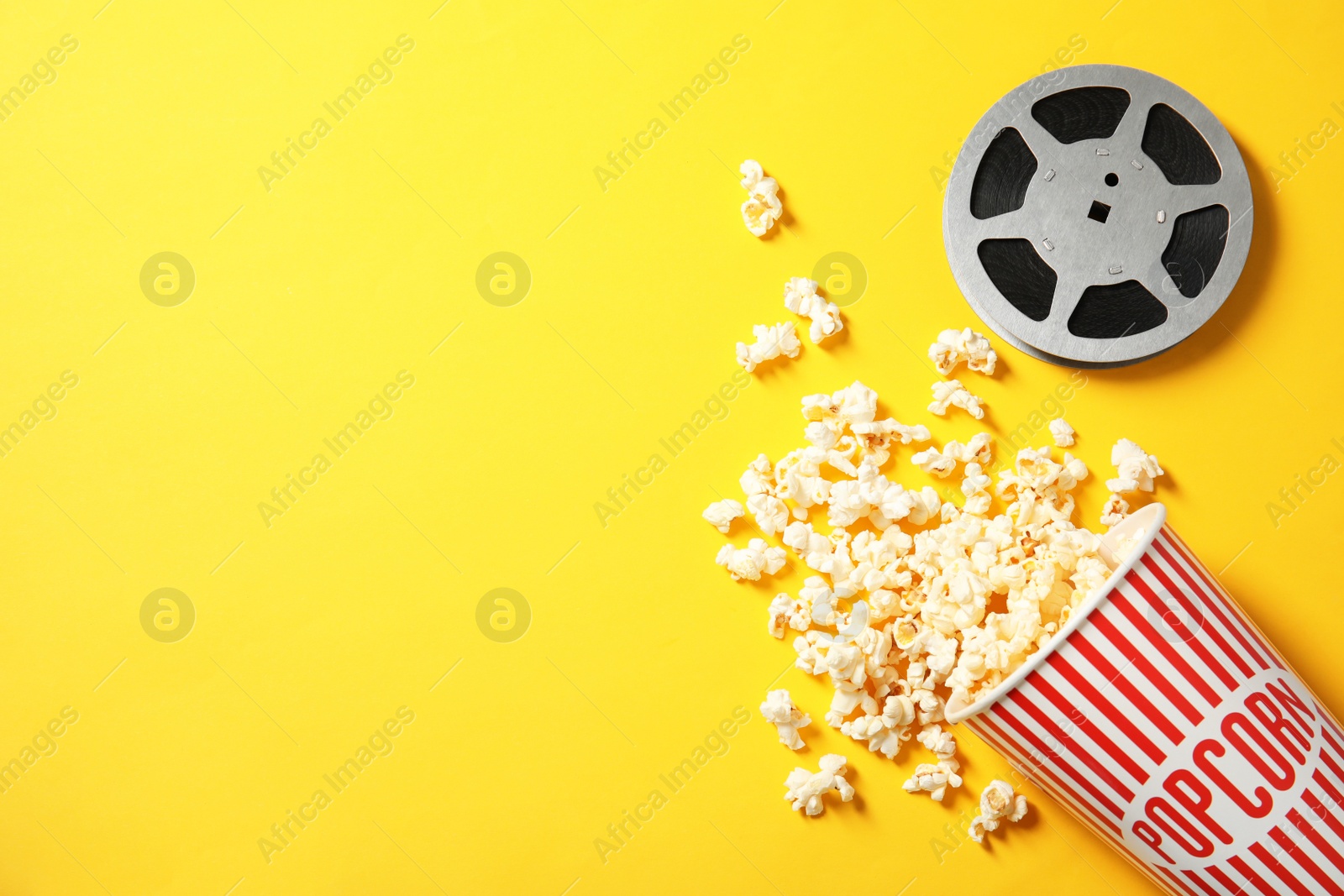 Photo of Flat lay composition with popcorn, reel and space for text on color background. Cinema snack