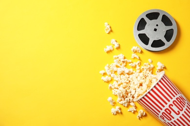 Flat lay composition with popcorn, reel and space for text on color background. Cinema snack