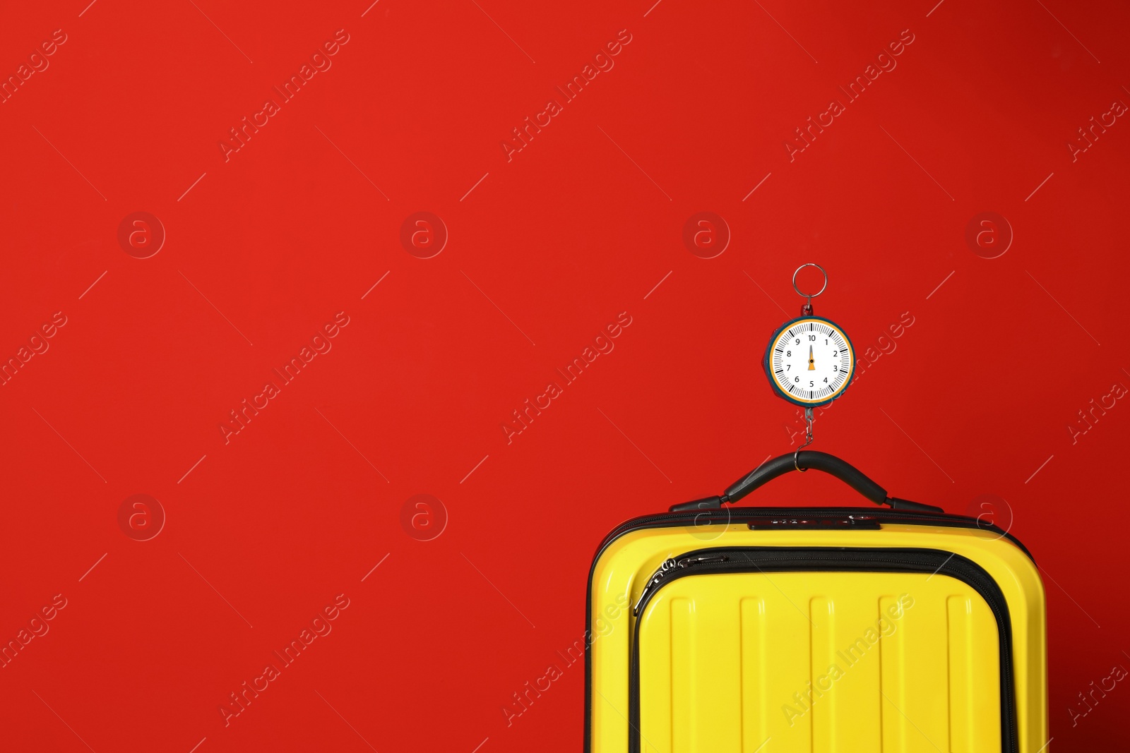 Photo of Modern suitcase and hanging scales against color background, space for text