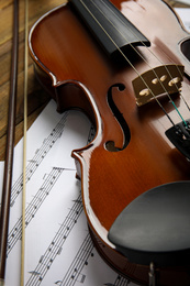Photo of Beautiful violin, bow and note sheets on wooden table