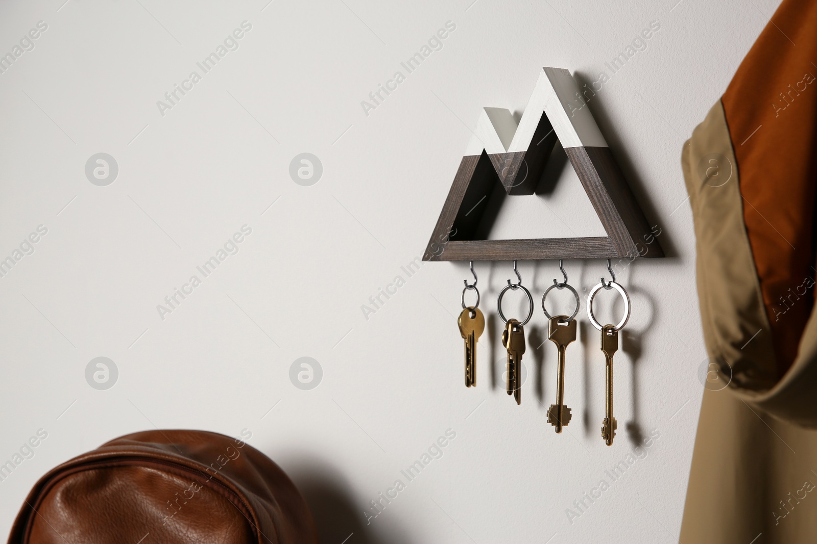 Photo of Wooden key holder on light wall indoors. Space for text