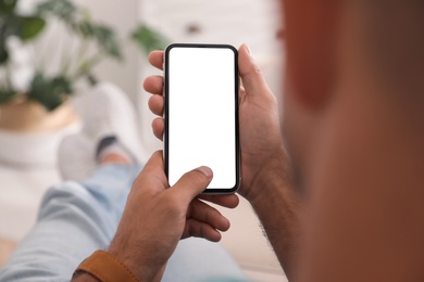 Man using mobile phone with empty screen indoors, closeup