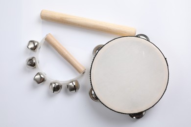 Wooden tambourine, rhythm stick and hand bells on white background, top view. Montessori musical toy