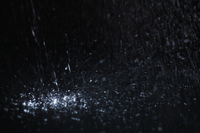 Photo of Heavy rain falling down on ground against dark background, closeup