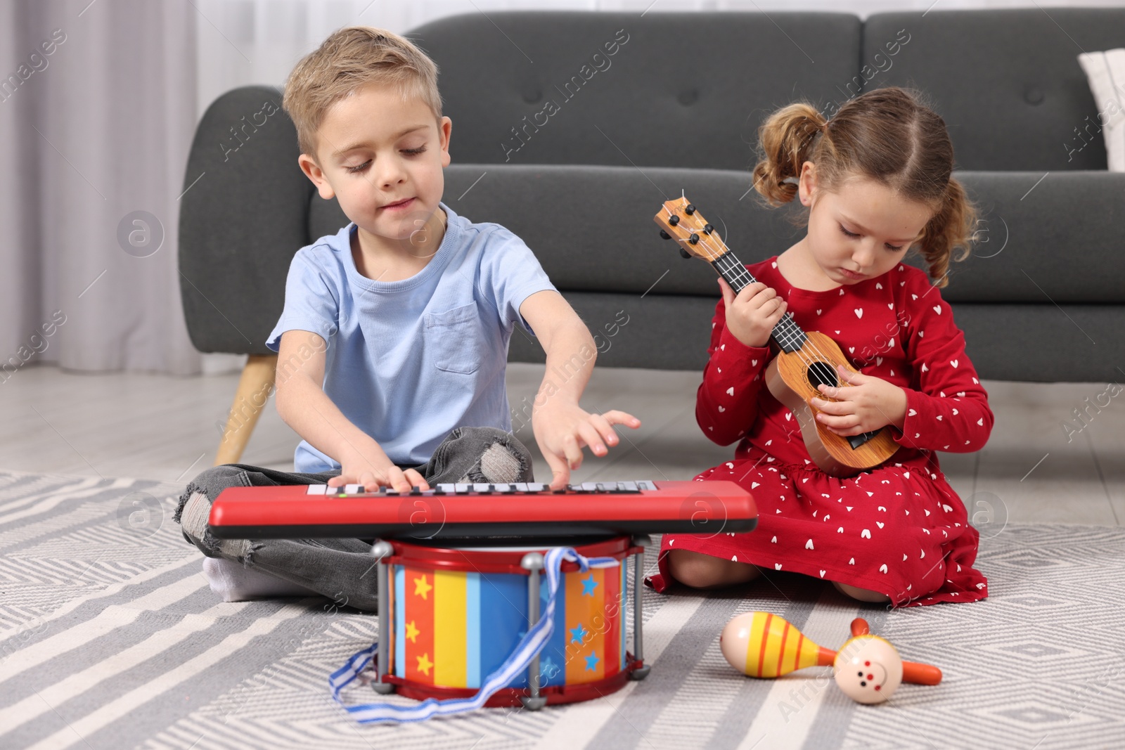 Photo of Little children playing toy musical instruments at home