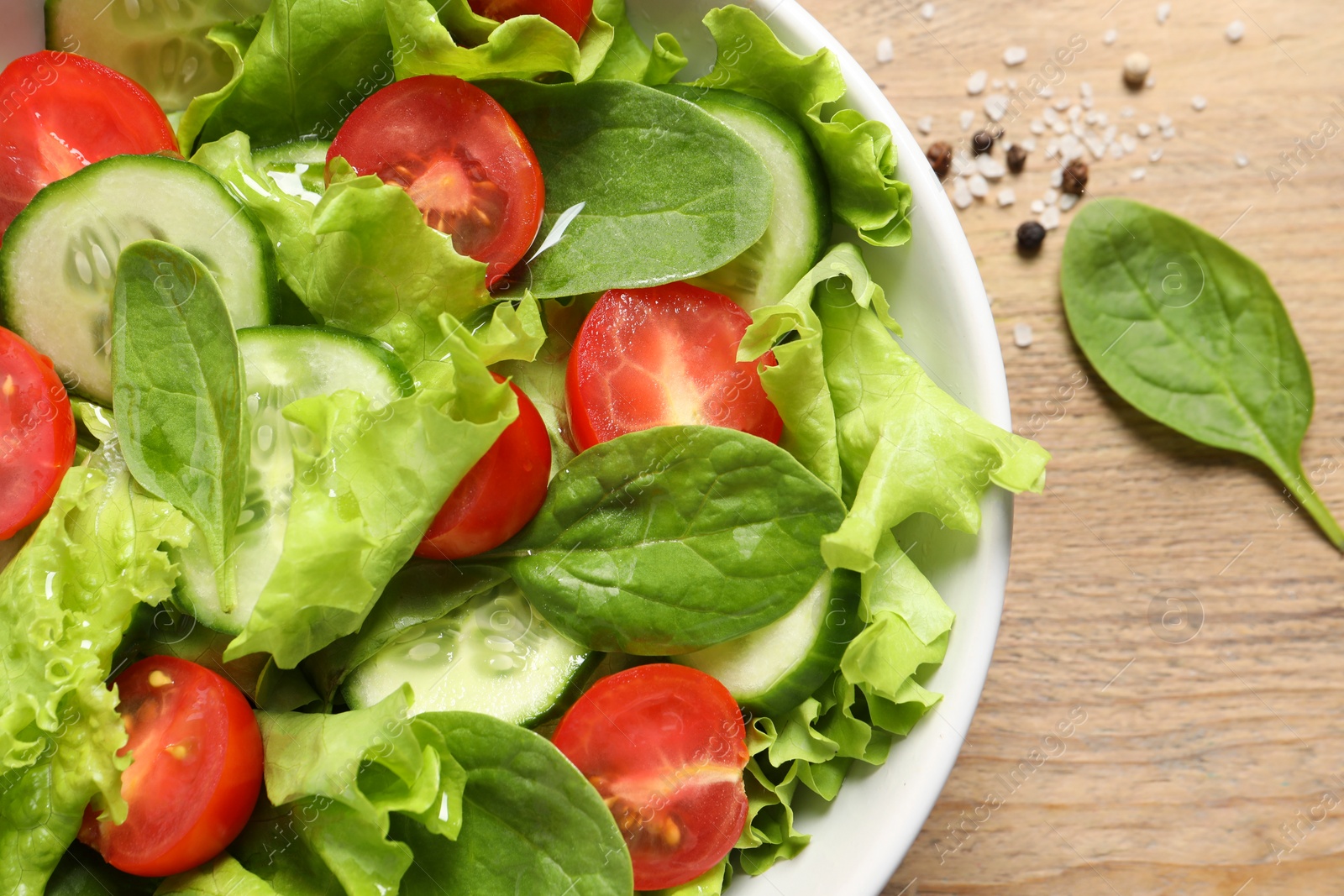 Photo of Delicious vegetable salad on wooden table, flat lay