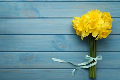 Photo of Beautiful daffodil bouquet on blue wooden table, top view. Space for text
