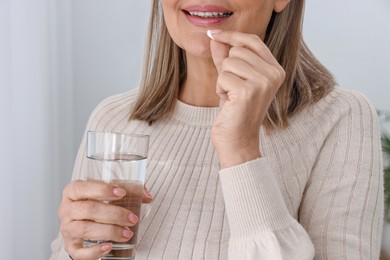 Photo of Woman taking vitamin pill at home, closeup