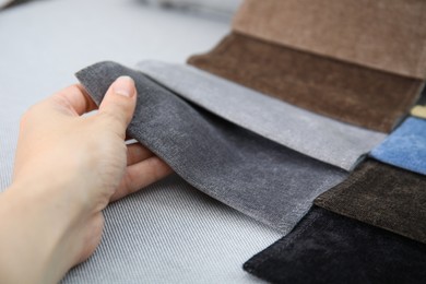 Photo of Woman choosing fabric among colorful samples on grey background, closeup