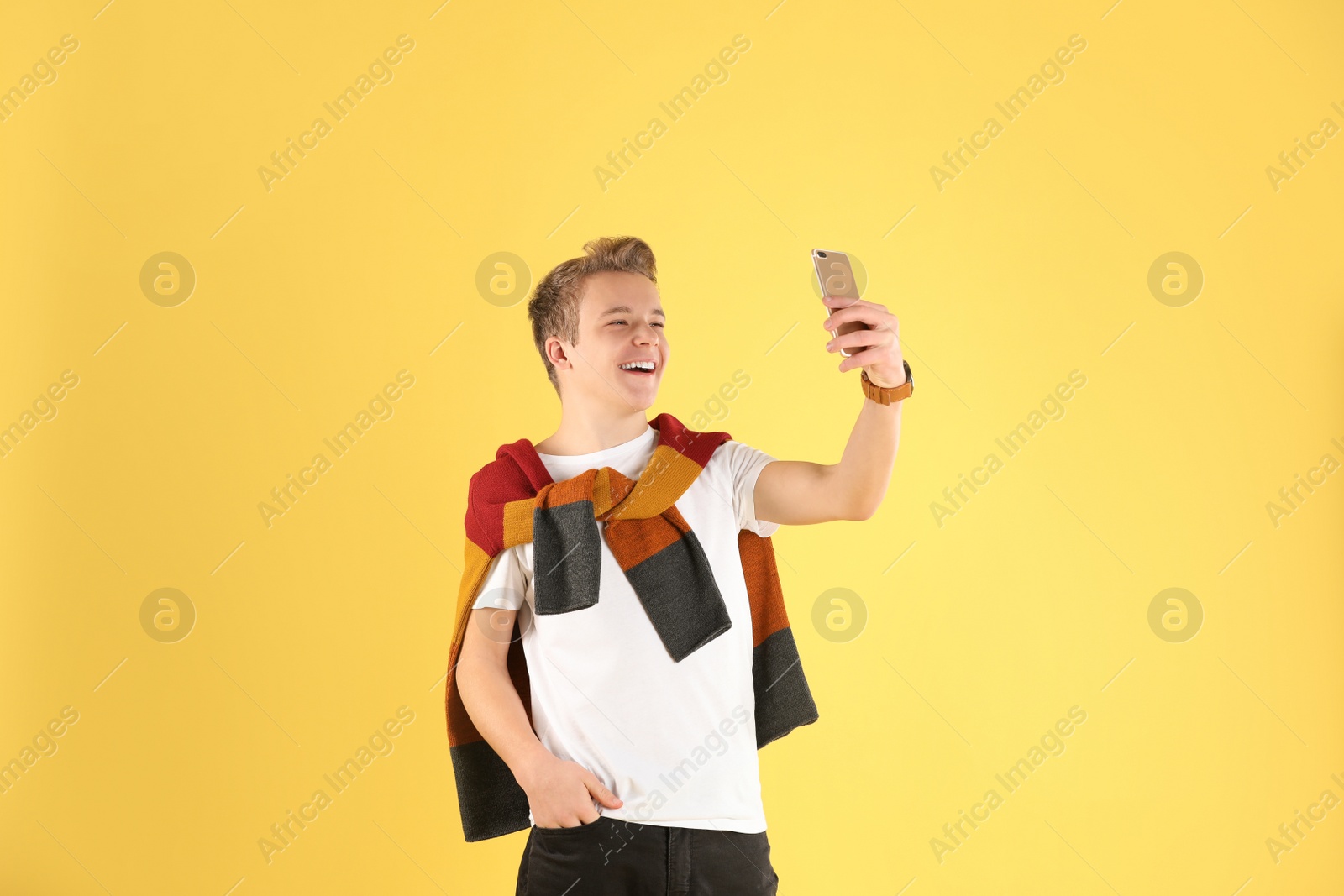 Photo of Handsome teenage boy taking selfie on color background