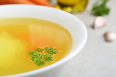 Photo of Delicious chicken bouillon with parsley on light grey textured table, closeup