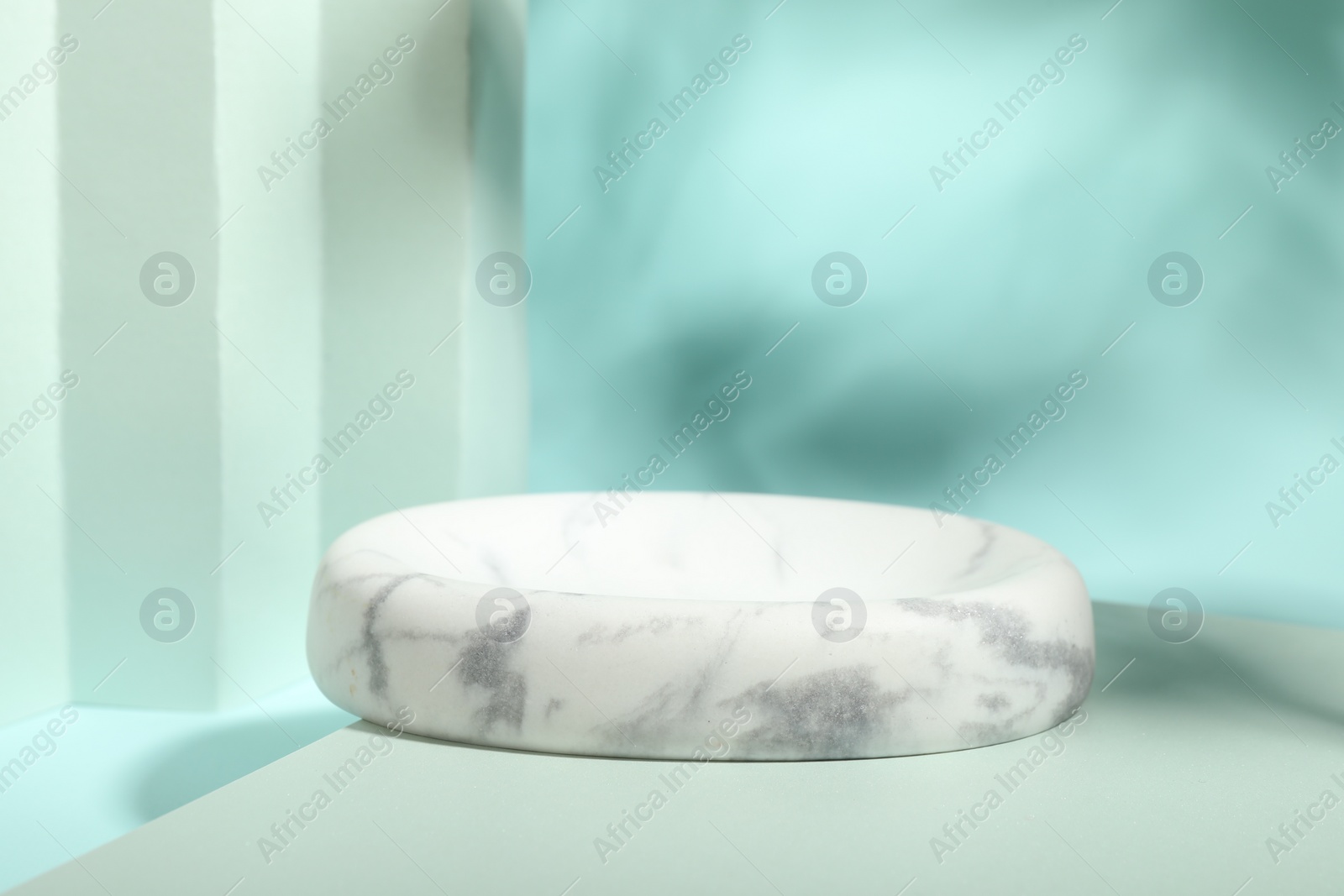 Photo of Presentation of product. Podium, paper and shadows on turquoise background. Space for text