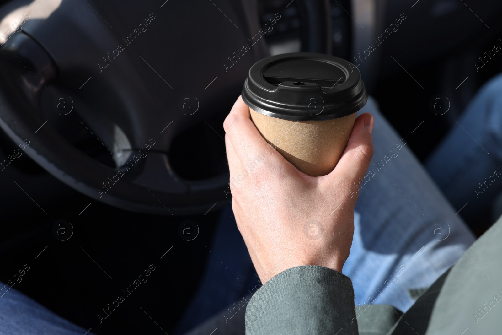 Photo of Coffee to go. Man with paper cup of drink in car, closeup