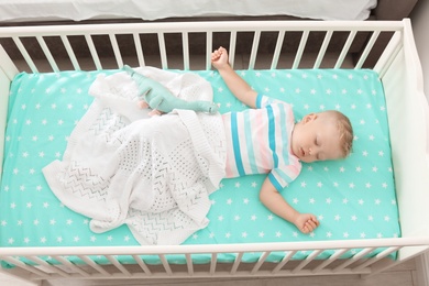 Cute little child sleeping in crib at home