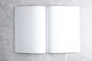 Photo of Blank open book on light grey marble background, top view. Mock up for design