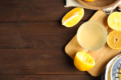 Photo of Freshly squeezed lemon juice on wooden table, flat lay. Space for text