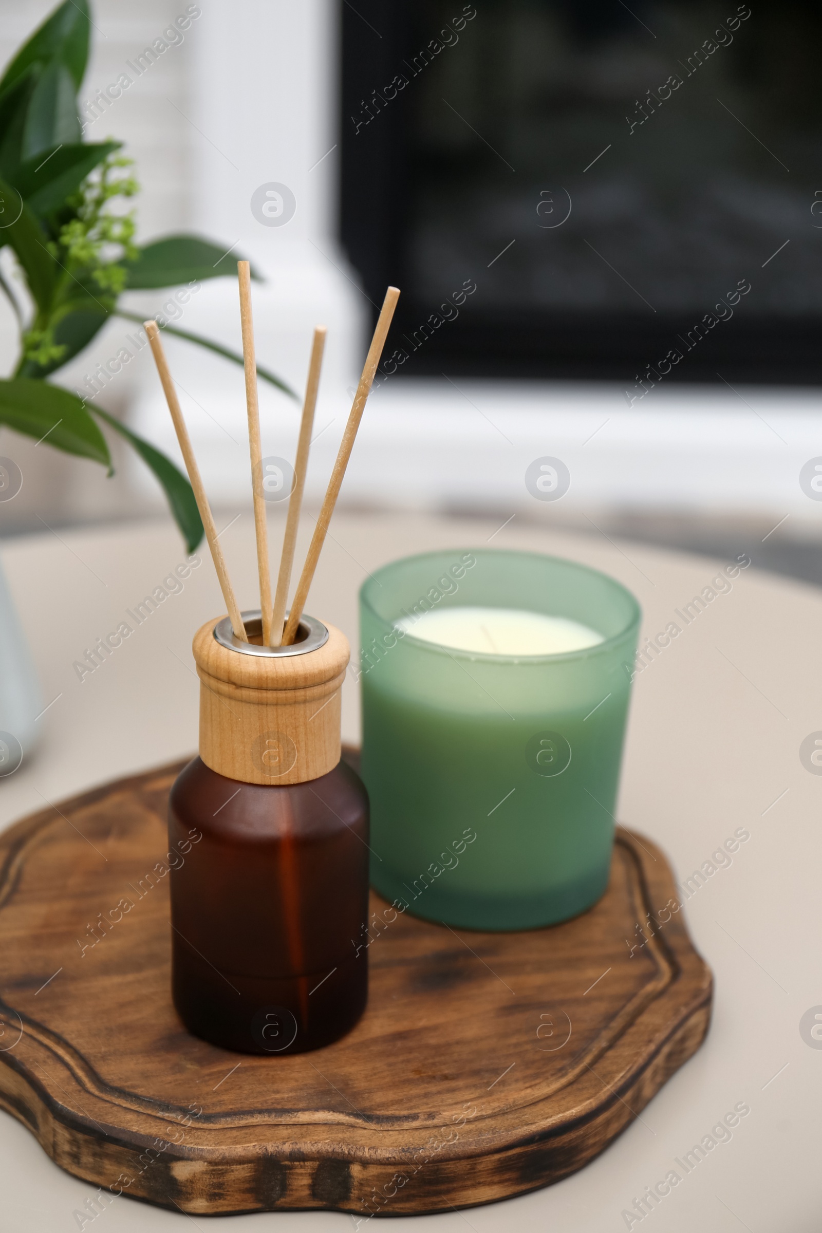 Photo of Reed air freshener and candle on table indoors