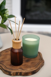 Photo of Reed air freshener and candle on table indoors