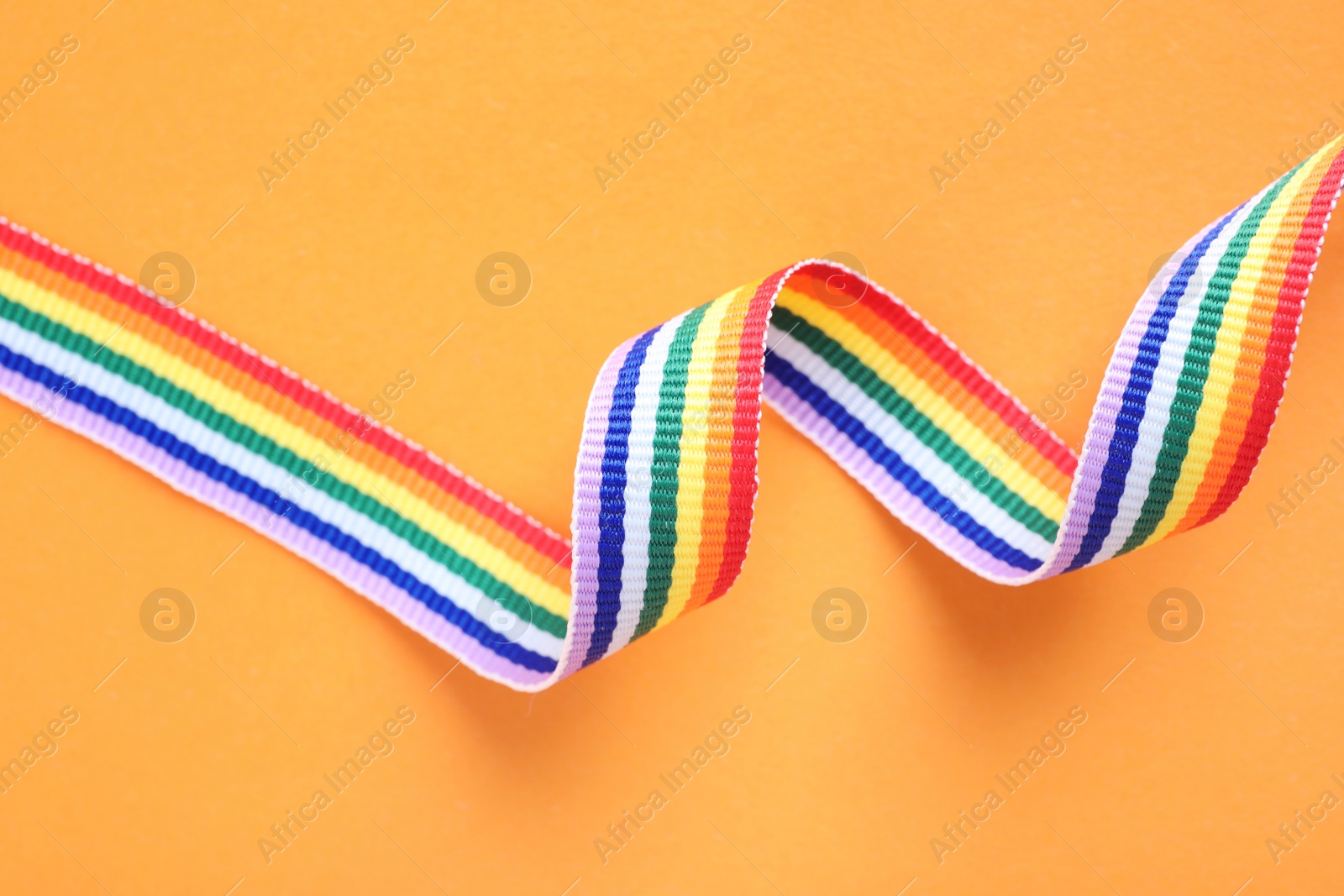 Photo of Bright rainbow ribbon on color background, top view. Symbol of gay community