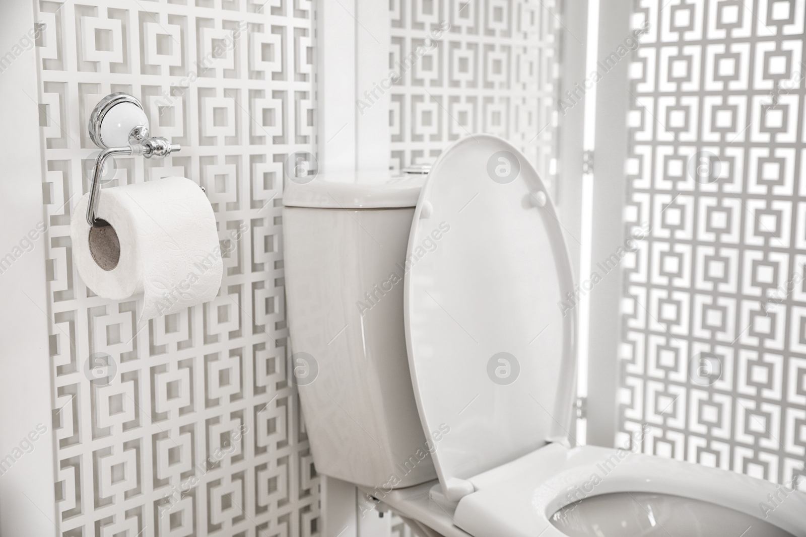 Photo of Modern toilet bowl and holder with new paper roll in bathroom