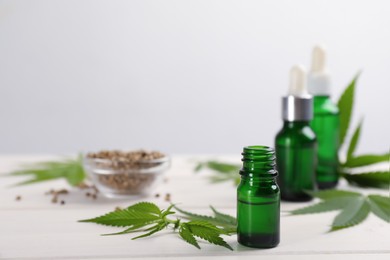 Photo of Hemp leaves, CBD oil and THC tincture on white wooden table, space for text