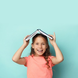 Photo of Portrait of cute girl with book on turquoise background. Reading concept