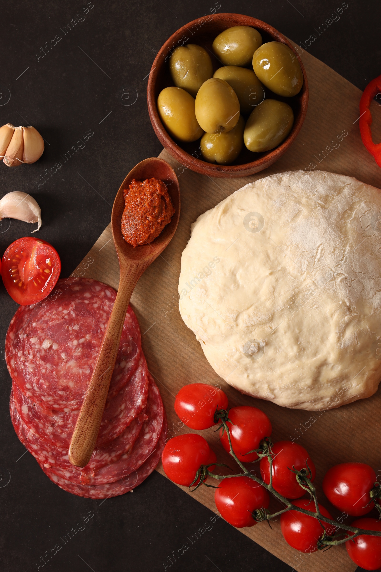 Photo of Pizza dough and products on dark table, flat lay