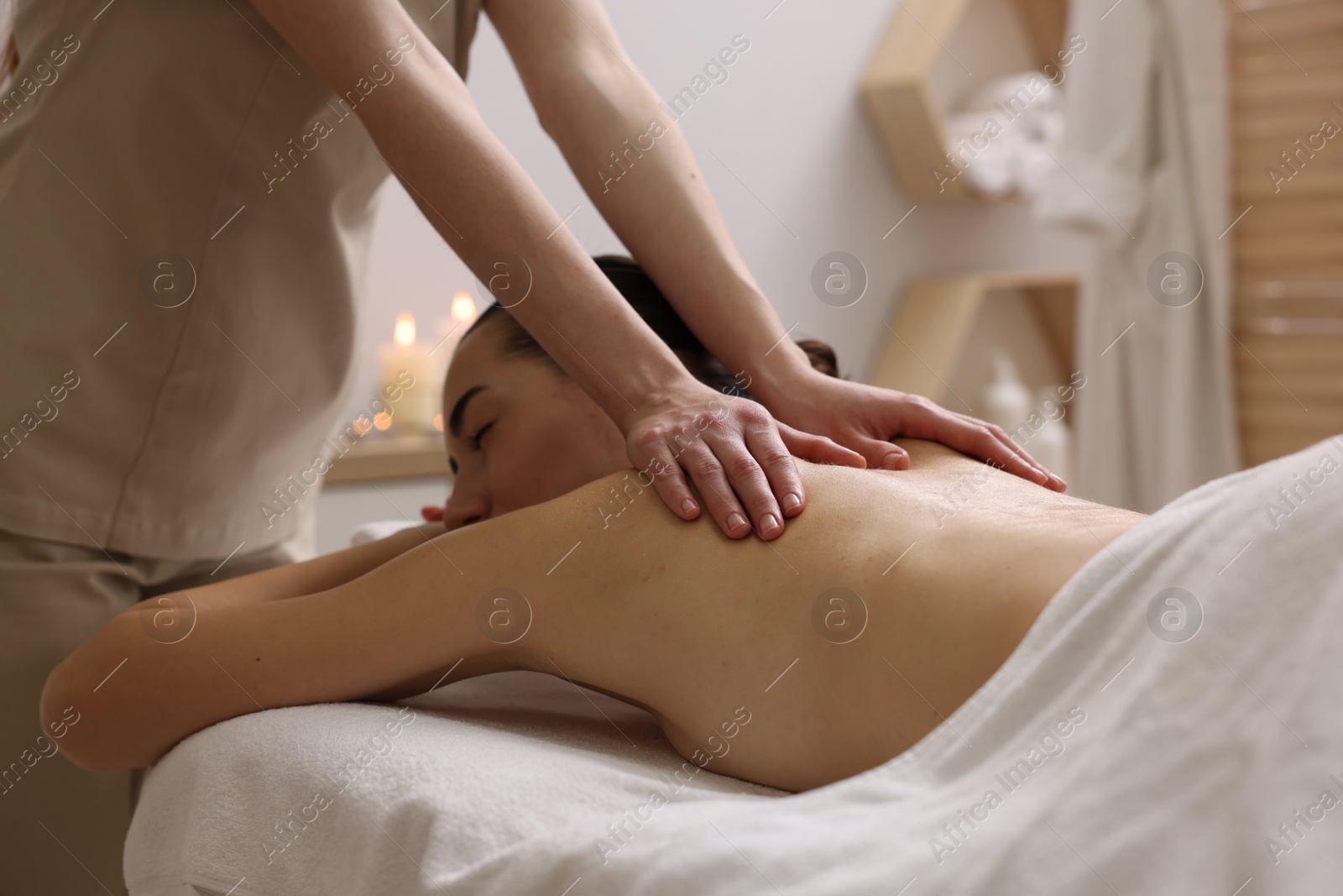 Photo of Woman receiving back massage on couch in spa salon